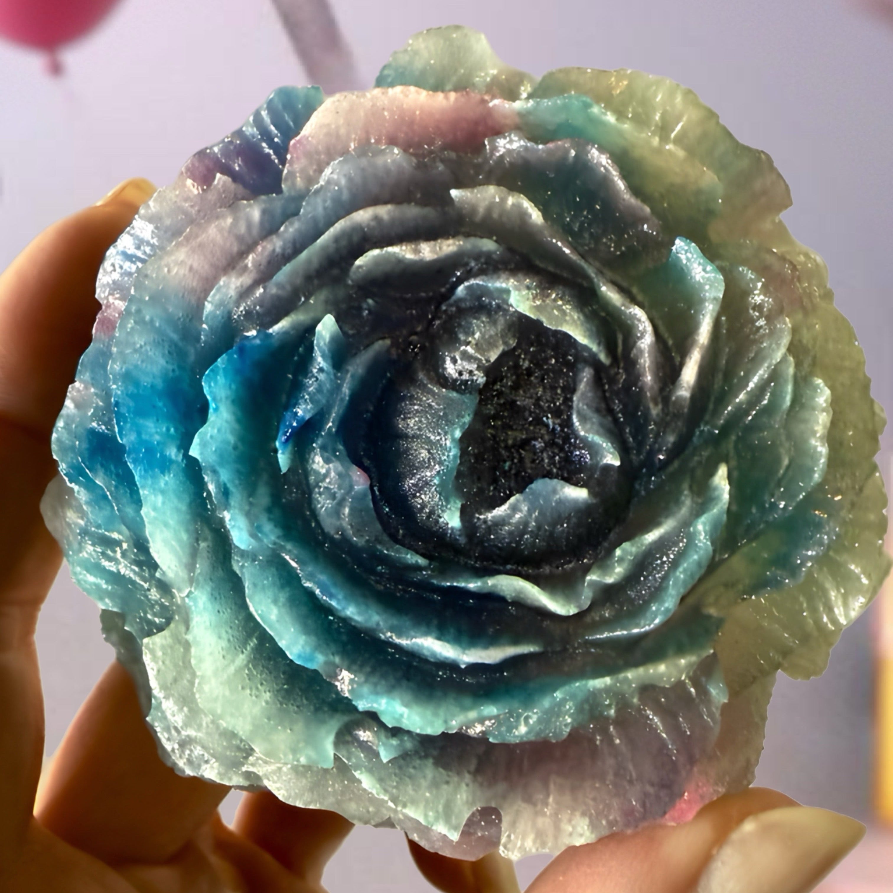 Multicolored flower-crystal candy  object held by a hand against a blurred background