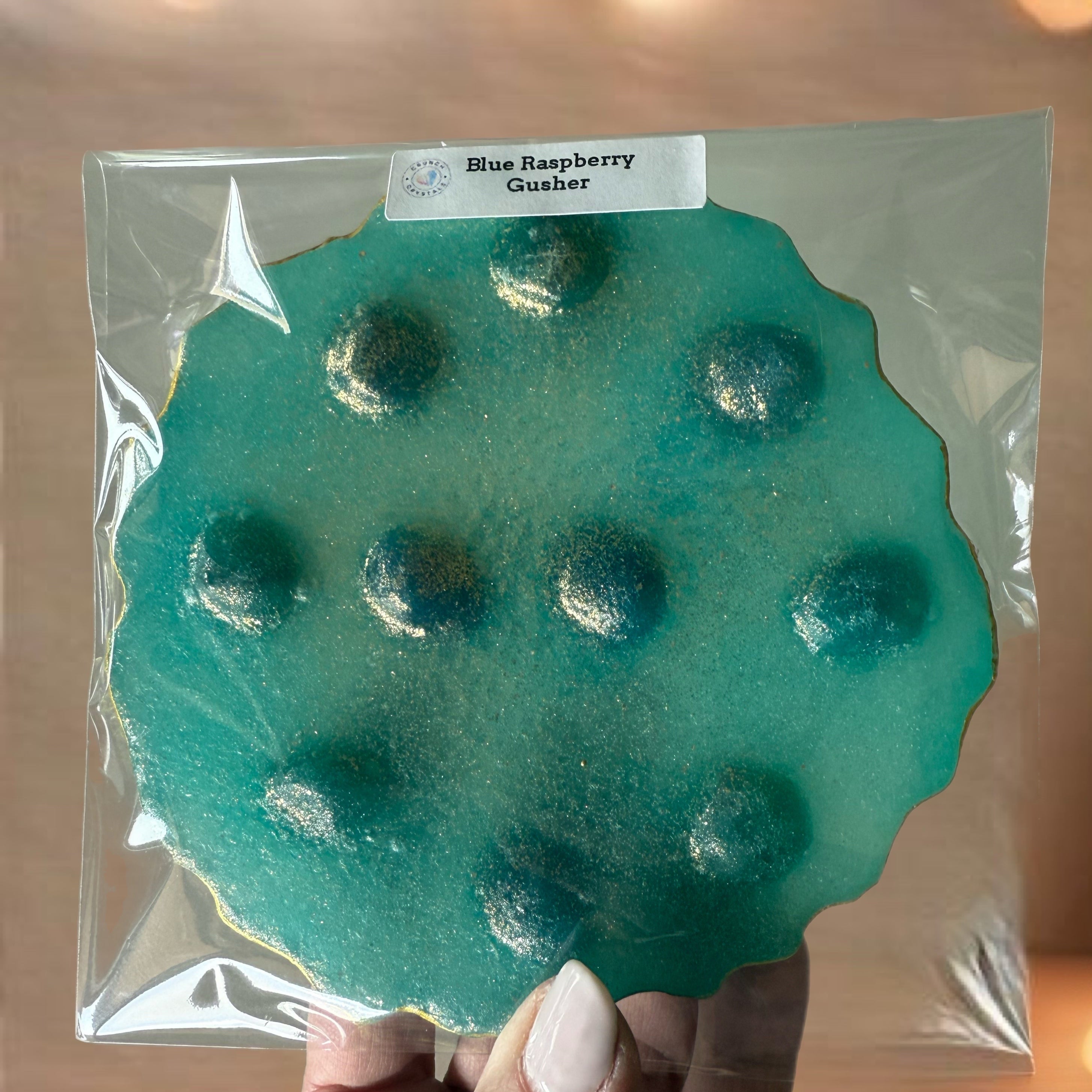 Blue raspberry gummy in a clear package held by a hand with a blurred background