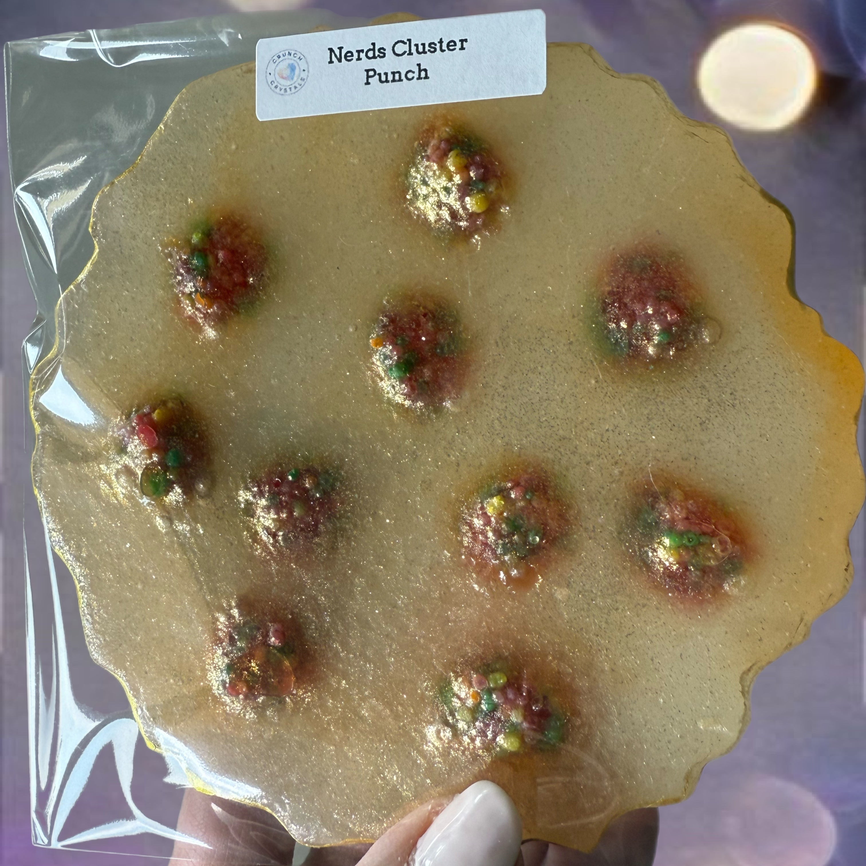 Packaged candy with Nerds clusters sprinkles held by a hand against a blurred background